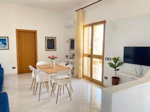 una sala da pranzo con tavolo e sedie bianche di Villa Mare Giuggiola ad Alcamo Marina