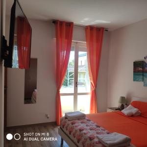 a bedroom with two beds with red curtains and a window at Da Mariolina in Alghero