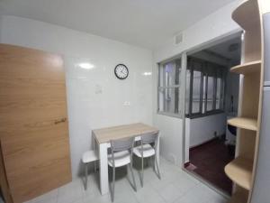 a dining room table with chairs and a clock on a wall at SOLPOR DO VERAN in Ribeira