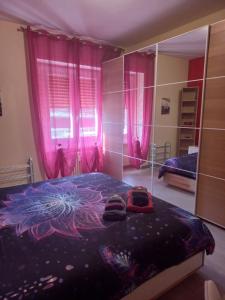 ローマにあるLady D Bed&Breakfastのピンクのカーテンと靴が付いたベッドが備わるベッドルーム1室が備わります。
