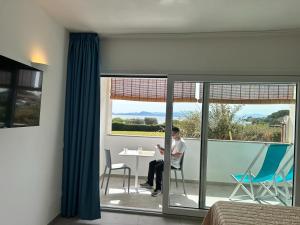 Rooms, affittacamere Maksim في غولفو أرانتْشي: رجل يجلس على طاولة أمام النافذة