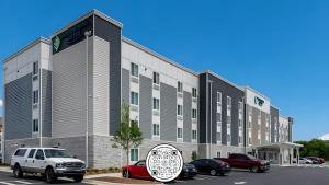 Un gran edificio con coches aparcados en un estacionamiento. en WoodSpring Suites Downers Grove - Chicago, en Downers Grove