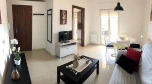a living room with a couch and a tv at Bella Recanati Apartment a Giardini Naxos in Giardini Naxos