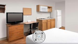 Habitación con cama, TV y cocina. en WoodSpring Suites St Louis Arnold en Arnold