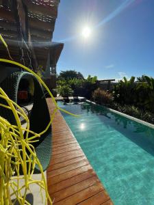 a swimming pool with a deck and chairs next to a building at Villa Meraki in Pipa