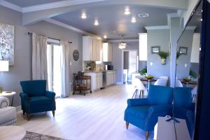 a living room with blue chairs and a kitchen at Country Cottage - Broussard in Broussard