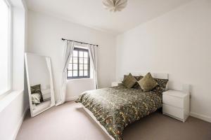 a white bedroom with a bed and a mirror at The Old Post Office - Norfolk Holiday Properties in Norwich
