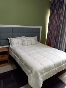 ein großes weißes Bett mit blauem Kopfteil in einem Zimmer in der Unterkunft HOTEL COMFORT in Quelimane