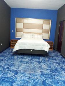 Schlafzimmer mit einem Bett mit blauer Wand in der Unterkunft HOTEL COMFORT in Quelimane