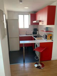 eine Küche mit roten Schränken und einem roten Stuhl in der Unterkunft El Ático de los Girondinos in Cádiz