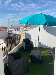 eine Terrasse mit Stühlen und einem Sonnenschirm auf dem Dach in der Unterkunft El Ático de los Girondinos in Cádiz