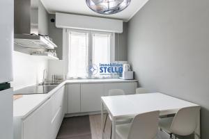 a white kitchen with a white table and chairs at Condominio Secchiati in Lido di Jesolo