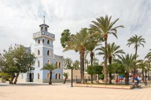 a white church with palm trees in front of it at 10 minutos de la playa in Asprillas
