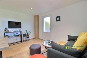 een woonkamer met een bank en een tv bij La Fleur de Vie in Pluneret