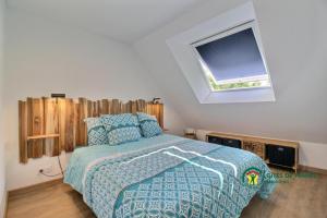 een slaapkamer met een bed met een blauw dekbed en een raam bij La Fleur de Vie in Pluneret