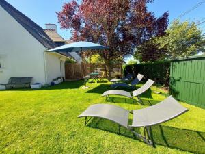 een groep stoelen en een paraplu in een tuin bij La Fleur de Vie in Pluneret