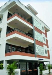 a tall white building with a balcony at ZIONS APERTMENT in Yelahanka