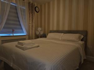 Schlafzimmer mit einem Bett mit weißer Bettwäsche und einem Fenster in der Unterkunft Comfortable Short Stay in Dublin in Dublin