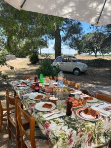 una mesa con comida y un coche en el fondo en Masseria Olga - Rural Coliving, en Turi