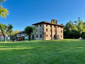 an old brick building in a field of grass at Villa Saten in Pavia dʼUdine