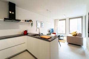 a white kitchen with a sink and a living room at Beautiful 1BR apartment in Antwerp in Antwerp