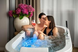 un homme et une femme assis dans une baignoire avec un verre de vin dans l'établissement Rota Apartments, à Rota d'Imagna