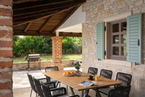 un patio con mesa de madera, sillas y parrilla en Rustic Villa Calluna with a pool in Istria, en Sveti Lovreč Pazenatički