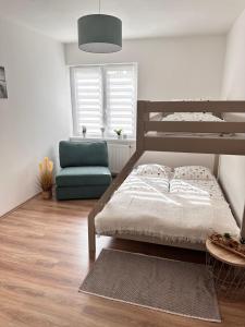 ein Schlafzimmer mit einem Bett und einem blauen Stuhl in der Unterkunft Apartmány Hřensko in Hřensko