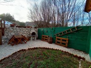 a backyard with a green fence and a stone wall at Brvnara Fairy Tale in Cetinje