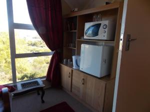 a room with a tv on a shelf with a window at Avondsrus Guesthouse in Bettyʼs Bay