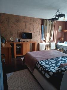 - une chambre avec un lit, une télévision et une table dans l'établissement Etno selo naša avlija, à Blace
