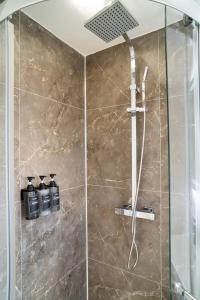 una doccia con porta in vetro e 3 bottiglie di Modern 2 Bedroom Home in Edinburgh Free Parking a Edimburgo