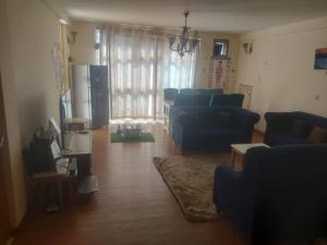 uma sala de estar com sofás azuis e uma televisão em Cozy Homestay Private Room: Home-Away-Home em Addis Ababa