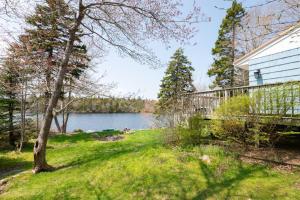 a house with a deck next to a body of water at Dreamy Lakefront View Retreat House on Melissa Ave in Terence Bay