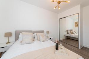 a white bedroom with a large white bed with a mirror at 2 Bed Exceptional Stay in Reading