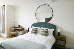 Un dormitorio con una cama grande y un espejo encima. en The Almshouse Suites, en Woburn Sands