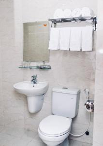 a white bathroom with a toilet and a sink at Quốc Khánh Hotel Da Nang in Da Nang