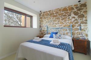 a bedroom with a bed and a stone wall at Casa del Pozo in Santillana del Mar