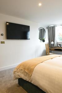 een slaapkamer met een bed en een flatscreen-tv aan de muur bij The Almshouse Suites in Woburn Sands