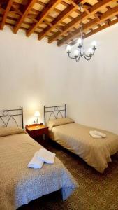 a bedroom with two beds and a chandelier at Casa La Sabina Roja 1 - Casa con impresionantes vistas sobre Hermigua y el mar in Hermigua