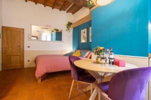 a bedroom with a bed and a table with purple chairs at Ardiglione Flat in Florence