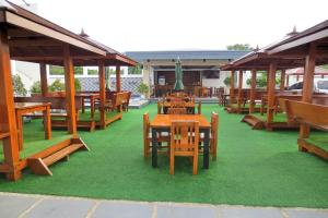 ein Restaurant mit Holztischen und Bänken auf grünem Gras in der Unterkunft Orient De Galera Beach Resort in Balatero