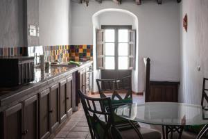 uma cozinha com uma mesa de vidro e cadeiras e um balcão em Casa Rural Los Sentidos Jimena em Jimena de la Frontera