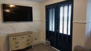 uma sala de estar com uma televisão, uma cómoda e uma janela em Scottish Nest in the heart of East Kilbride 10mins from Hairmyres Hospital em East Kilbride