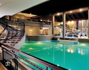 une grande piscine d'eau bleue dans un bâtiment dans l'établissement Cameron House - Lodge 17 - Loch Lomond, à Balloch