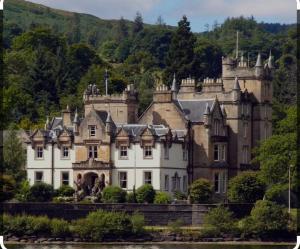 a large castle sitting on the side of a river at Cameron House - Lodge 17 - Loch Lomond in Balloch