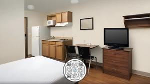 a kitchen with a tv and a desk with chairs at WoodSpring Suites Lincoln Northeast I-80 in Lincoln
