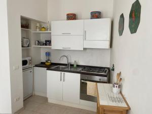 a kitchen with white cabinets and a sink and a stove at Oleander House apartments in Torri del Benaco