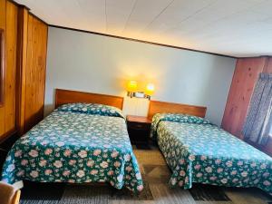 um quarto de hotel com duas camas e duas lâmpadas em Sun N Snow Hotel em Cadillac