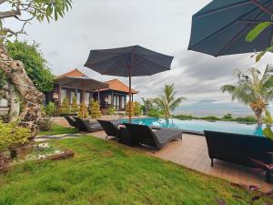 a pool with chairs and umbrellas next to a house at Nusa Sedayu Hotel By Ocean View in Nusa Penida